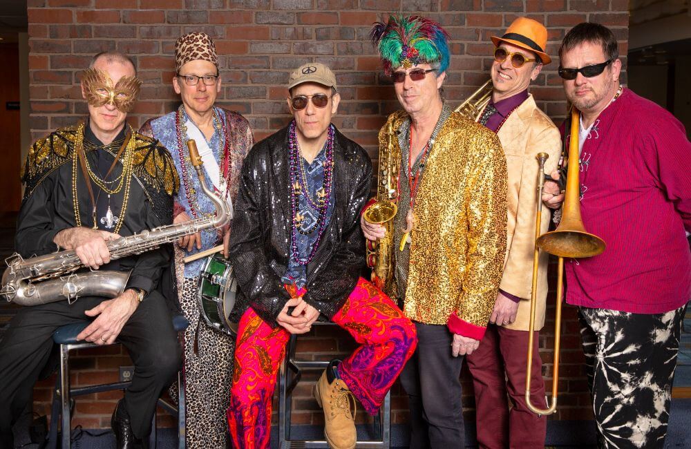 Six people in colorful outfits and sunglasses