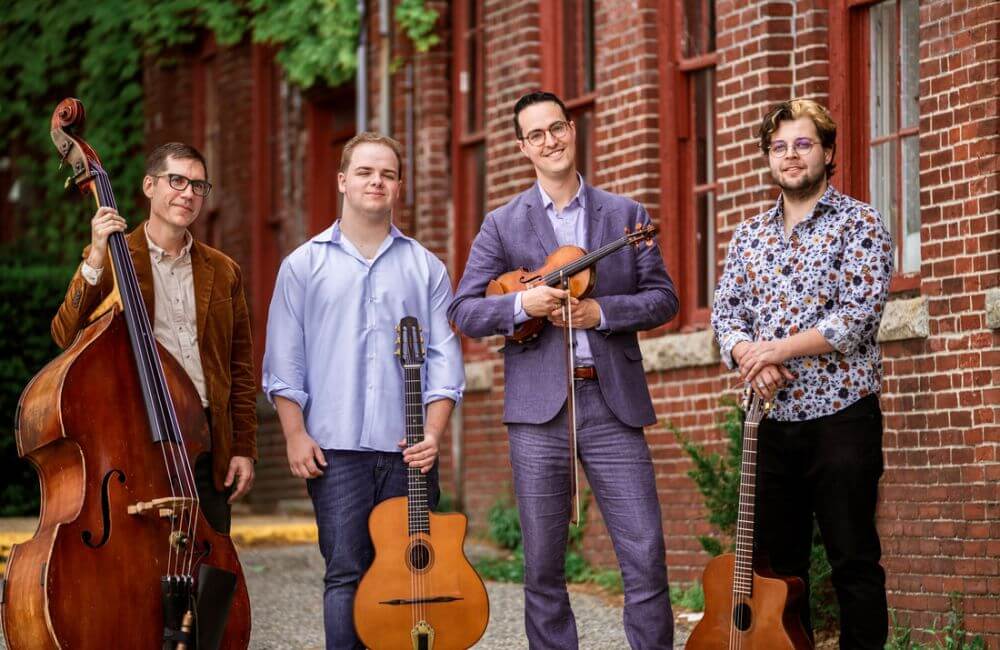 Quartet standing together in formal clothes in front of a brick building