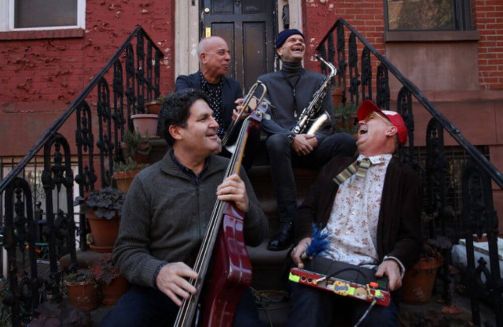 Group of musicians smiling together on a staircase of a brownstone