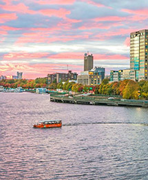 Boston Duck Tour boat driving in the river with the city skyline in the back