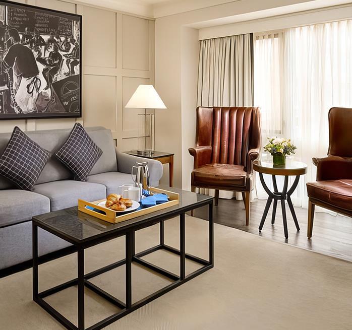 a room with a grey couch, black coffee table and two brown chairs
