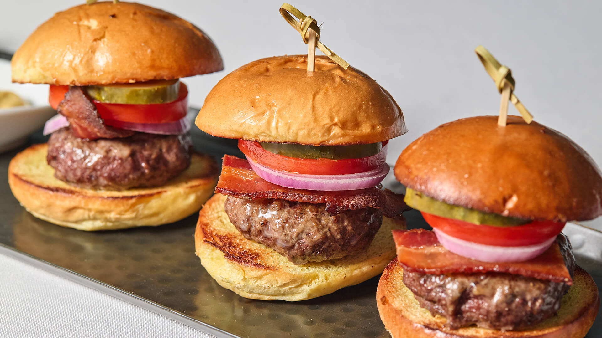 Burger sliders with bacon, tomato, red onion, and pickle