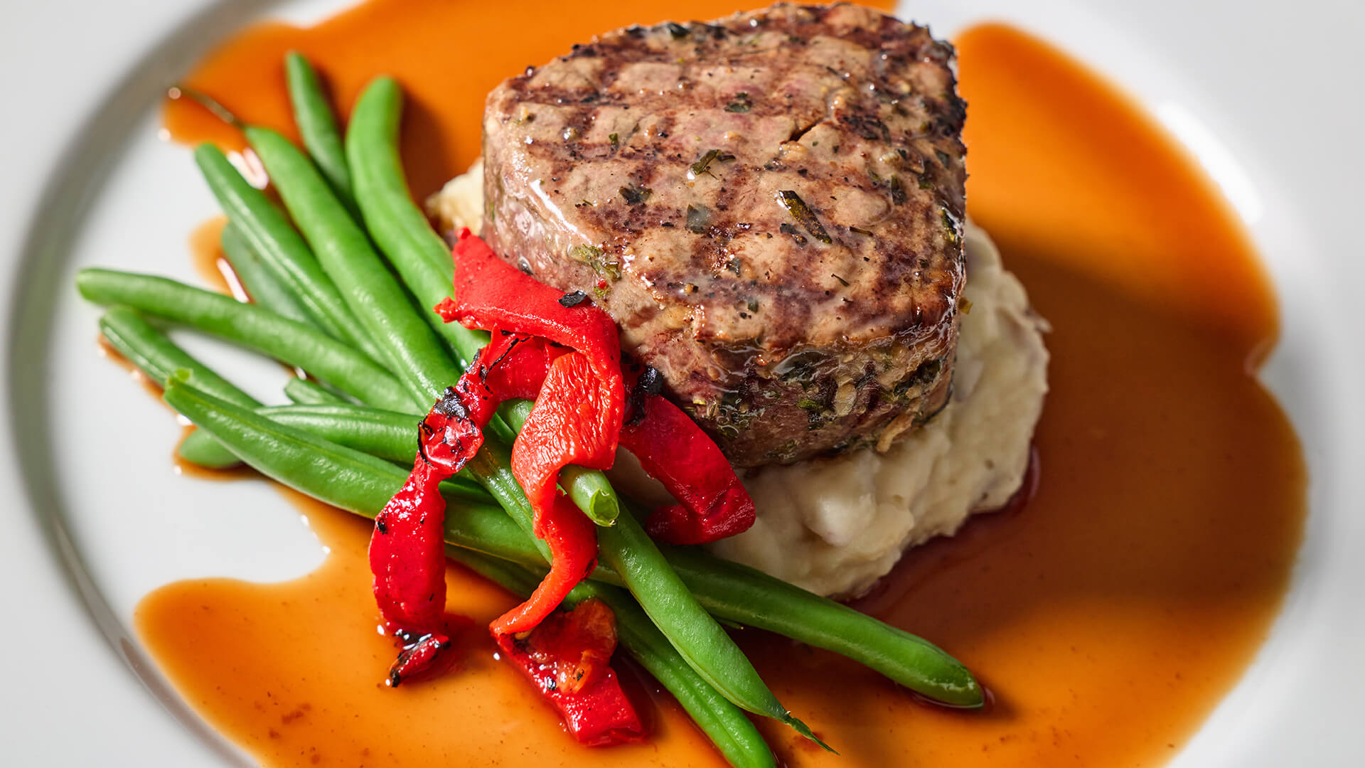 Steak with green beans on a mound of mashed potatoes