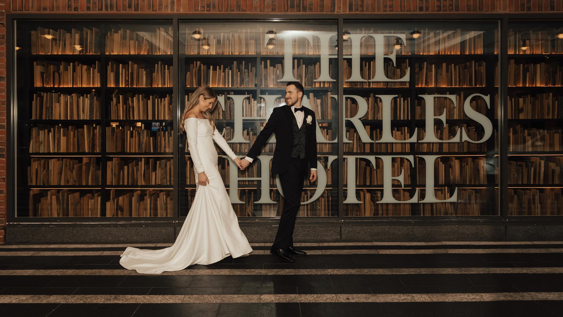Wedding couple in front of The Charles Hotel lobby with books