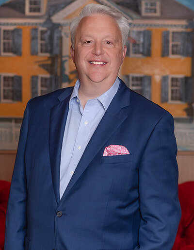Adam Sperling in a navy blue suit with a pastel blue dress shirt and a pink pocket square