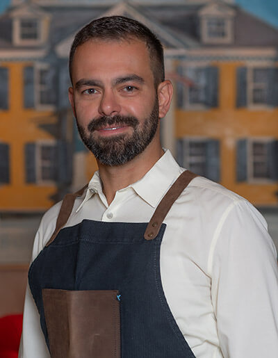 Augusto Lino Barbosa in a navy blue and and brown apron and a white dress shirt