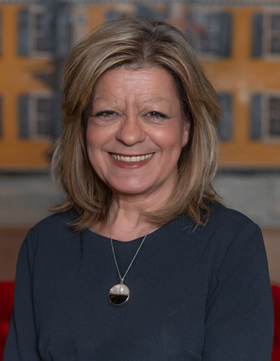 Maureen Albright in a navy blue peplum top with a pendant necklace
