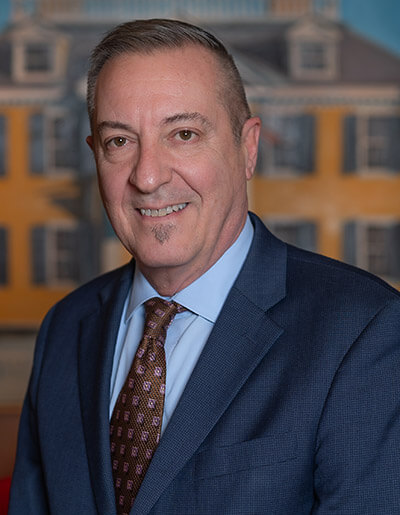 Anastasios Papatsoris in a navy blue jacket with a pastel blue dress shirt and a brown dress tie with a square pattern