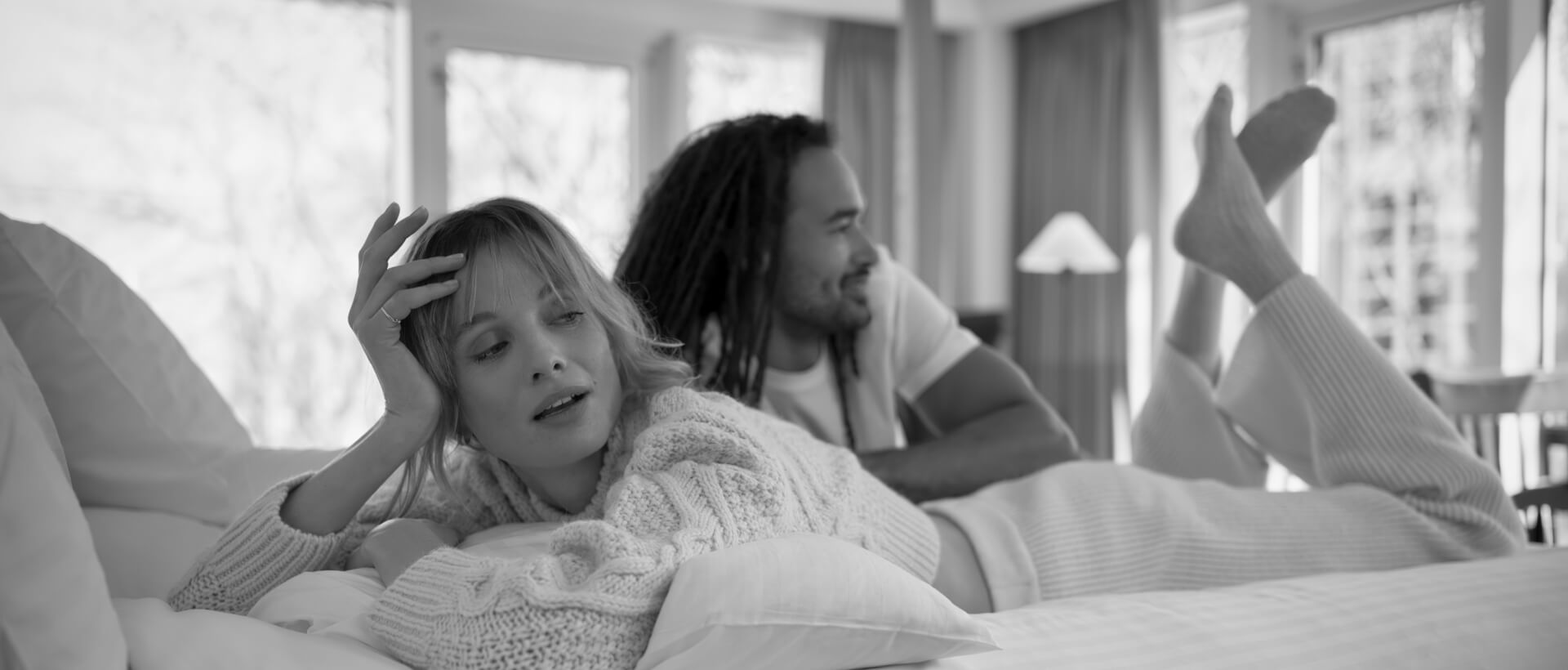 a man and a woman lounging on hotel bed