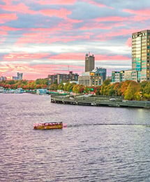 Boston Duck Tour boat driving in the river with the city skyline in the back